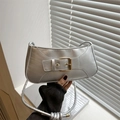 Sleek silver underarm bag with metallic finish and gold buckle detail held by hand - Silver