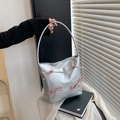 Silver metallic tote bag with pink bow accents shown in an elegant lifestyle setting - Silver