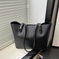 Minimalist black leather tote bag with FASHION lettering by a sunlit window - Black
