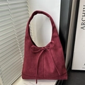 Bolso tote de ante burdeos con detalle de lazo en un entorno interior con luz natural - Rojo