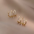 Close-up of four-claw gold ear cuffs with micro-pave white zircons on silk background - Four-Claw Studs - Yellow Gold