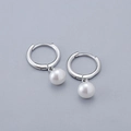 Primer plano de pendientes minimalistas de plata con perlas blancas de alto brillo - Pendientes de Aro de Perlas / Oro Blanco