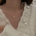 Elegant gold flower necklace with sparkling zircon petals worn on a soft white knit sweater - Gold