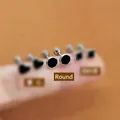 Macro shot of mini black heart, round, and square enamel stud earrings on a fingertip - Round Enamel Stud Earrings