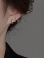 Dettaglio di orecchini a cerchio ritorti in argento con trama raffinata indossati - Huggie in Zirconia Intrecciata