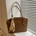 Brown leather tote bag with decorative silk scarf on a clean minimalist background - Tan