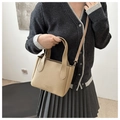 Close-up of tan lychee texture bucket bag with dual handles and embossed logo - Khaki