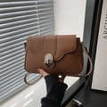 Schicke braune Baguette-Tasche mit Silberschnalle und verstellbarem Riemen in Handansicht - Braun