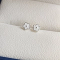Detailed macro view of white enamel five-petal flower earrings on a textured cushion - Drip Glue Flower Screw Stud Earrings - White