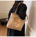 Detail of beige textured leather tote bag showing side zipper and double straps on model - Khaki