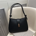 Chic black vintage PU leather shoulder bag with antique bronze clasp on white chair - Black