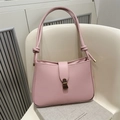 Pink minimalist underarm handbag with knotted strap and bronze buckle on white chair - Pink