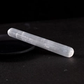Polished white selenite crystal healing wand on black tray with natural fiber texture - Cylindrical Massage Wand