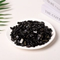 Polished natural black obsidian crystal chips displayed in a white ceramic plate - Obsidian