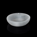 Round white selenite crystal bowl for charging and healing on black reflective surface - Round