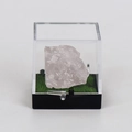 Raw rose quartz crystal specimen in a transparent display case with green turf base - Rose Quartz