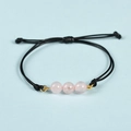 Minimalist black rope bracelet featuring three pink quartz beads with golden accents - Rose Quartz