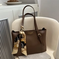 Brown leather tote bag with elegant floral silk scarf handle on a white chair - Dark Brown