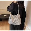 Model wearing a gray hobo tote bag with vertical zippers and side pockets in a modern room - Gray