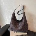 Modische Hobo-Tasche mit Leopardenmuster und schwarzem Leder-Schultergurt auf Buch - Kaffeebraun