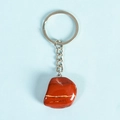 Polished red jasper tumbled stone keychain with silver metal ring on blue background - Red Jasper