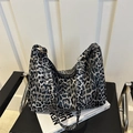 Grande borsa shopper con stampa leopardata e tracolle regolabili su una sedia nera - Nero