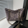 Schicke Leoparden-Tote-Bag mit schwarzen Leder- und Goldkettenriemen auf der Fensterbank - Khaki