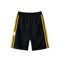 Flat lay of black cotton kids sports shorts featuring bright yellow side stripes - 130cm / Black