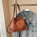 Bruine suède bucket bag met trekkoordsluiting en stijlvolle lederen textuurvlakken - koffiekleur