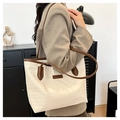 Detailed close-up of large cream-white tote bag with dark brown straps and fashion text - Brown
