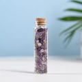 Natural amethyst gravel in a clear glass bottle with cork stopper on blue background - 5-7mm Chips / Amethyst