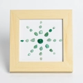 Square wooden frame with green raw crystals arranged in a sunflower sunburst pattern - Green Aventurine