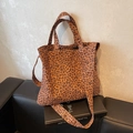 Detailaufnahme der Leoparden-Einkaufstasche mit breitem Gurt auf einem Ledersofa - Braun