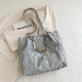 Detalle de bolso tote plateado plisado con colgante de perla y mariposa sobre un blazer - Plateado
