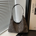 Vintage-Schultertasche mit Leopardenmuster und schwarzen Lederriemen am Fenster - Hellbraun