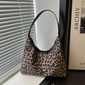 Leopard print hobo tote bag with black leather straps shown in a stylish indoor setting - Khaki