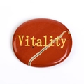 Ovale rode jaspis duimsteen met gouden Vitality gravure op witte achtergrond - Rode Jaspis: Vitaliteit