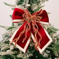 Fiocco di Natale in velluto rosso con bordi dorati su un albero di Natale innevato - Borgogna