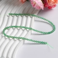 Perles d'aventurine verte pour création de bijoux sur fond blanc texturé - Type Quatre