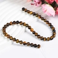 Natural tiger eye stone beads on white textured background with cat eye effect - 8mm