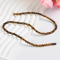 Golden tiger eye round loose beads for DIY jewelry making on white textured display - 4mm