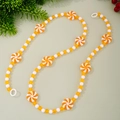 Weihnachtsgirlande mit orangefarbenen Pfefferminzbonbons und festlichen Quasten - Gelb