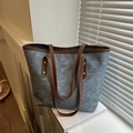 Large gray felt tote bag with brown leather handles and gold rivets in a sunlit room - Blue