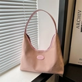 Minimalistische roze suède hobo schoudertas met logo op een vensterbank - Roze