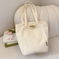 Minimalist cream white canvas tote bag with fashion label on soft white sofa - Off White