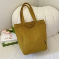 Vertical mustard yellow canvas tote bag with minimalist FASHION label on white sofa - Khaki