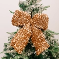 Sparkling champagne gold sequin bow ornament hanging on a snowy Christmas tree branch - Large Yellow