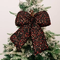 Christmas bow ornament with red sequins on black fabric hanging on a snowy tree branch - L Black
