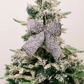 Sparkling grey sequin Christmas bow ornament hanging on a snowy Christmas tree branch - Small Gray