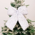 Sparkling white Christmas bow ornament with silver sequins on a snowy pine tree branch - Large White